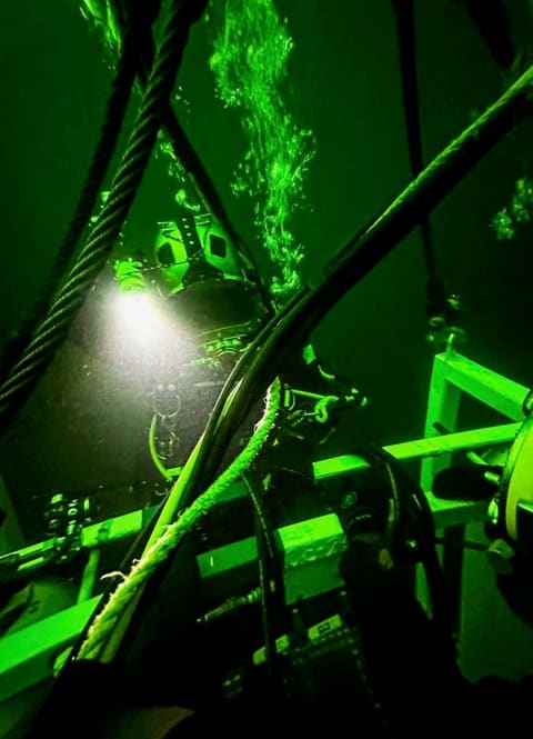 Diver with a helmet light inspecting steel structure underwater inside a water tank